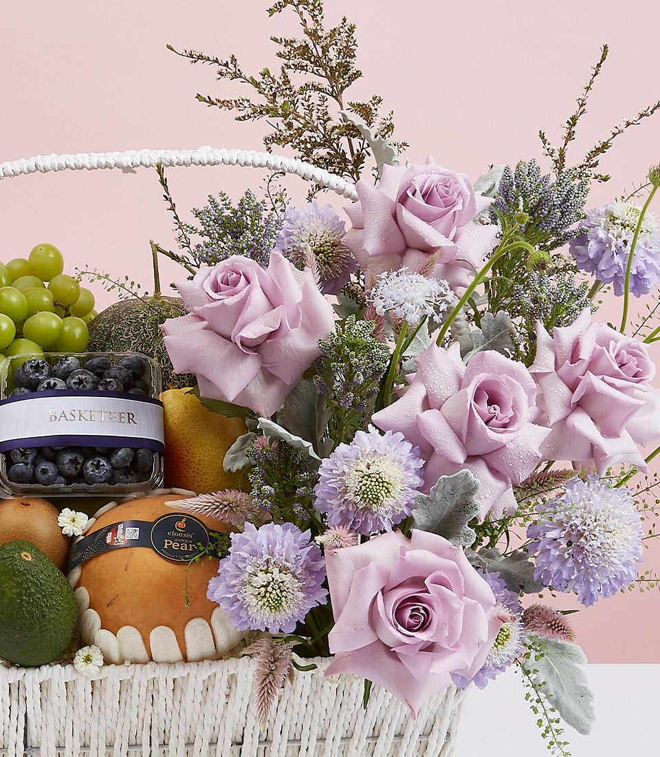 Fresh fruit and purple roses gift basket with grapes, berries, pears, and seasonal blooms