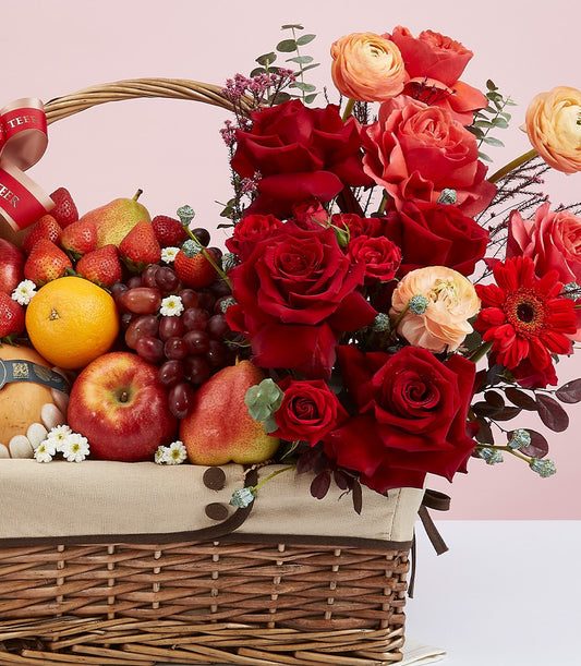 Woven wicker gift basket with fresh fruit and vibrant rose bouquet arrangement for celebrations