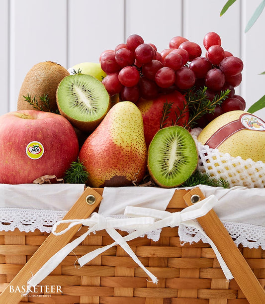 Woven fruit gift basket with fresh apples, kiwis, grapes, pears and white ribbon bow