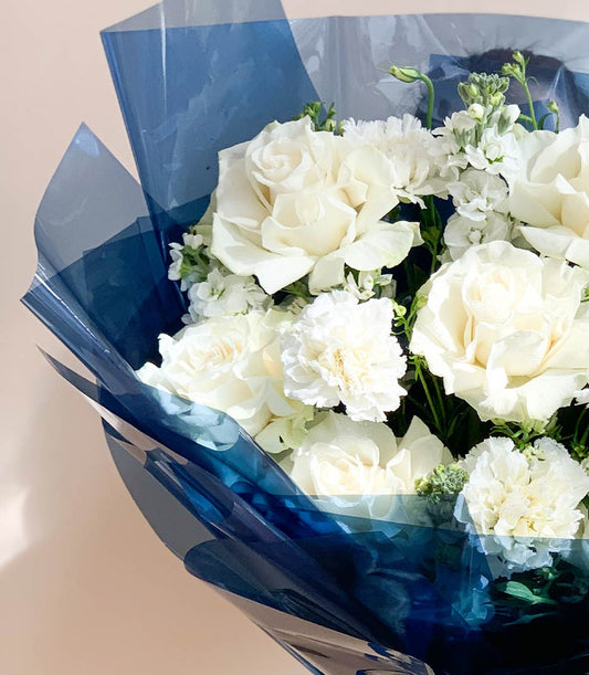 Graceful white roses and carnations bouquet in dark blue cellophane wrapping, fresh Ecuador blooms for gifting