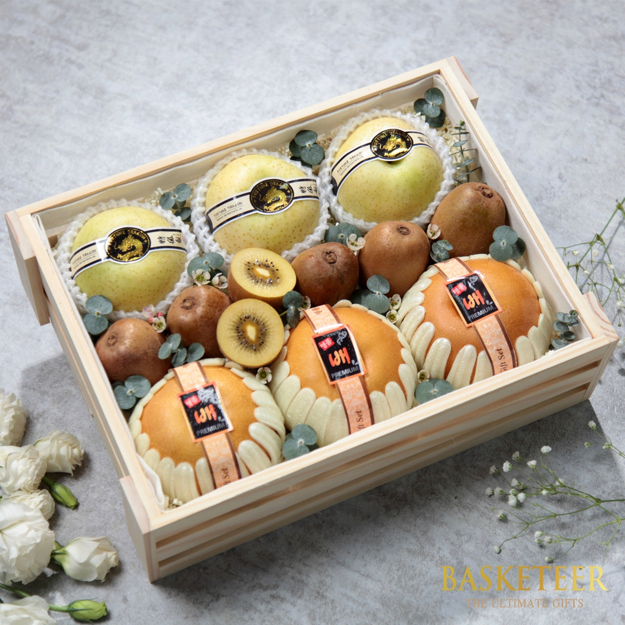 Wooden crate filled with fresh pears, kiwis, and greenery in premium gift presentation