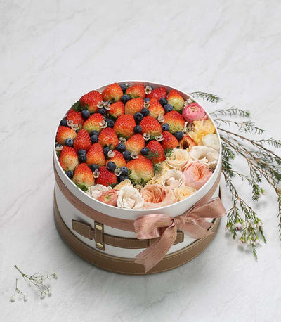 Premium berry and flower gift box with fresh strawberries, blueberries, roses, and ranunculus in vintage white hatbox with
