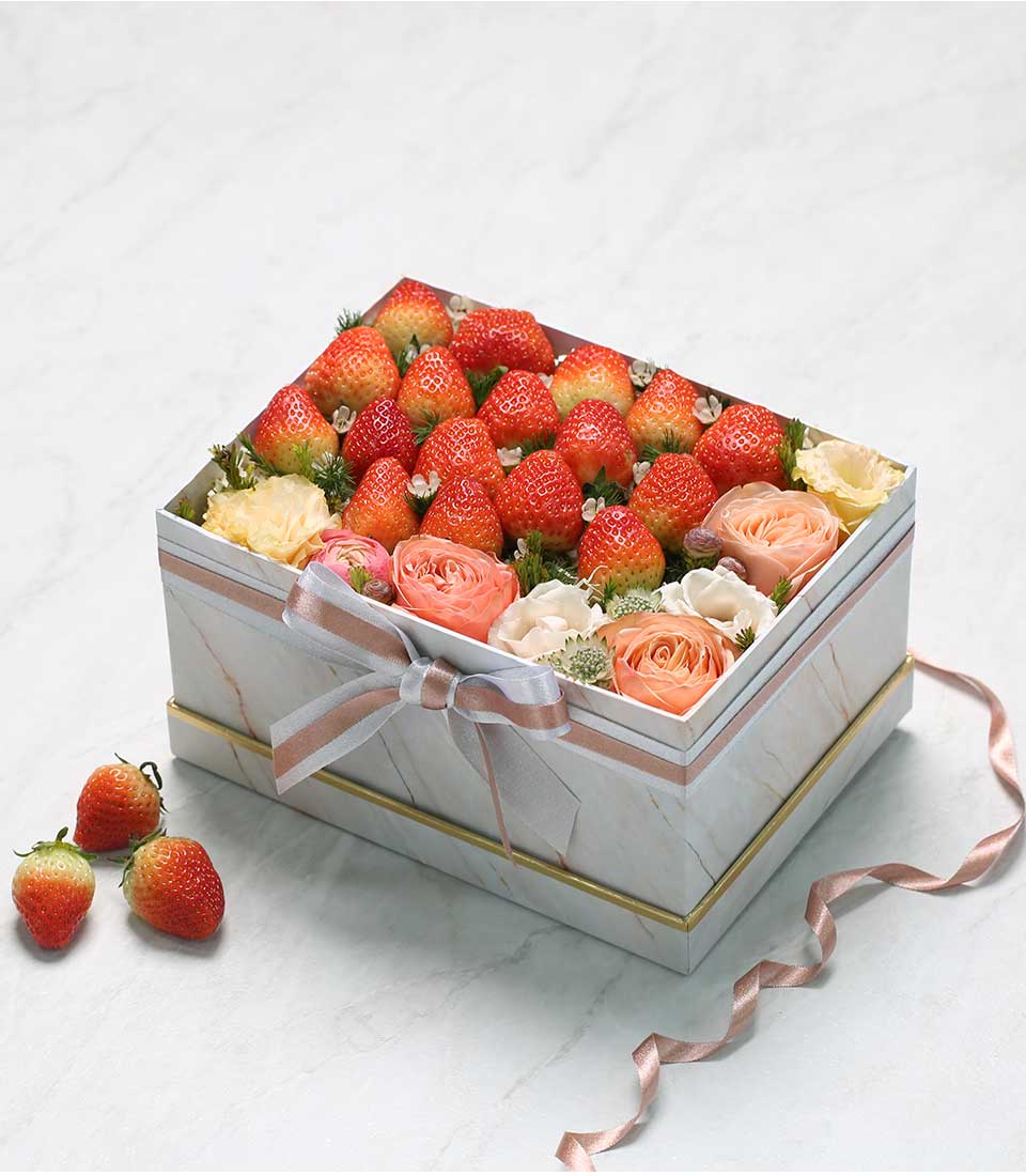 Fresh strawberries and peach roses in elegant white marble gift box with rose gold trim