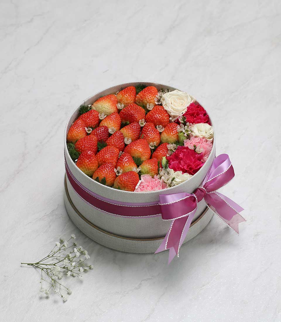 Fresh strawberries and white roses in luxury grey gift box with pink ribbon