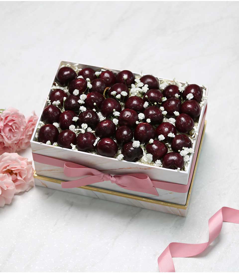 Luxury cherry gift box with marble pattern, pink ribbon, and fresh roses for elegant gifting