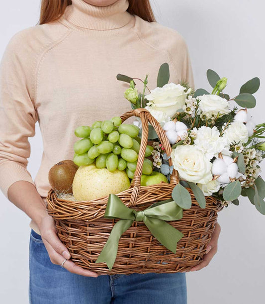 Premium wicker basket with fresh grapes, pears, apples, kiwi and white roses, carnations with eucalyptus and sage ribbon