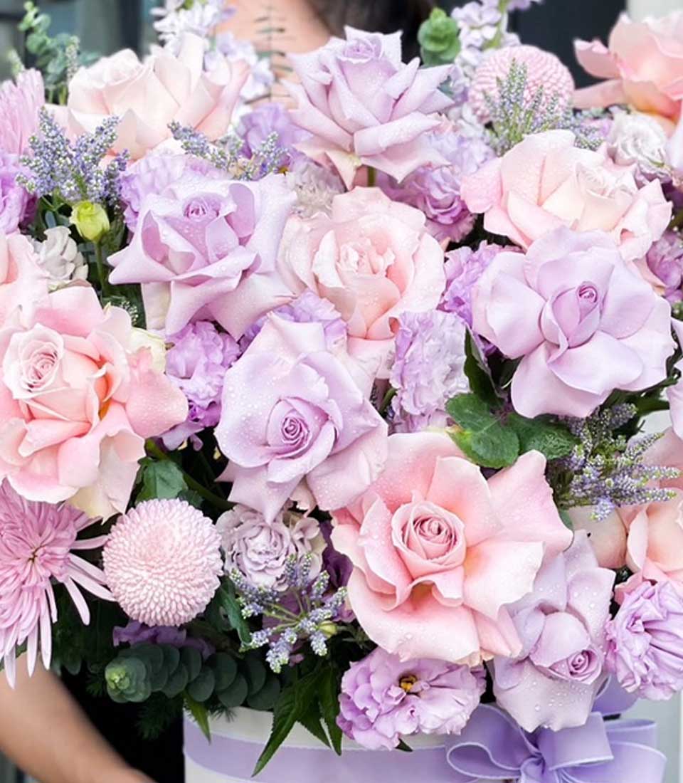 Pink and lavender rose bouquet with purple blooms in white striped hatbox, fresh celebration flowers