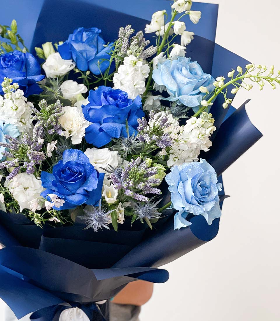 Vibrant blue and white rose bouquet with lavender and thistle, navy wrap, premium fresh flower gift