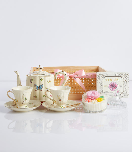 Cream teapot and teacups gift set with floral designs, English Rose Tea, and candle in woven basket with pink ribbon