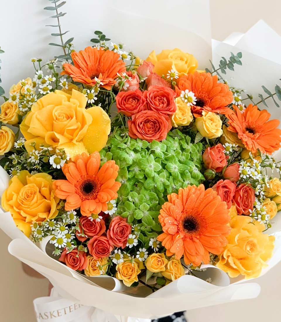Vibrant sunshine bouquet of orange gerberas, yellow roses, and white daisies with fresh water droplets