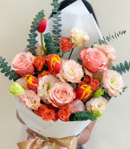 Vibrant mixed roses, tulips, and lisianthus bouquet in pink, orange, and yellow with eucalyptus