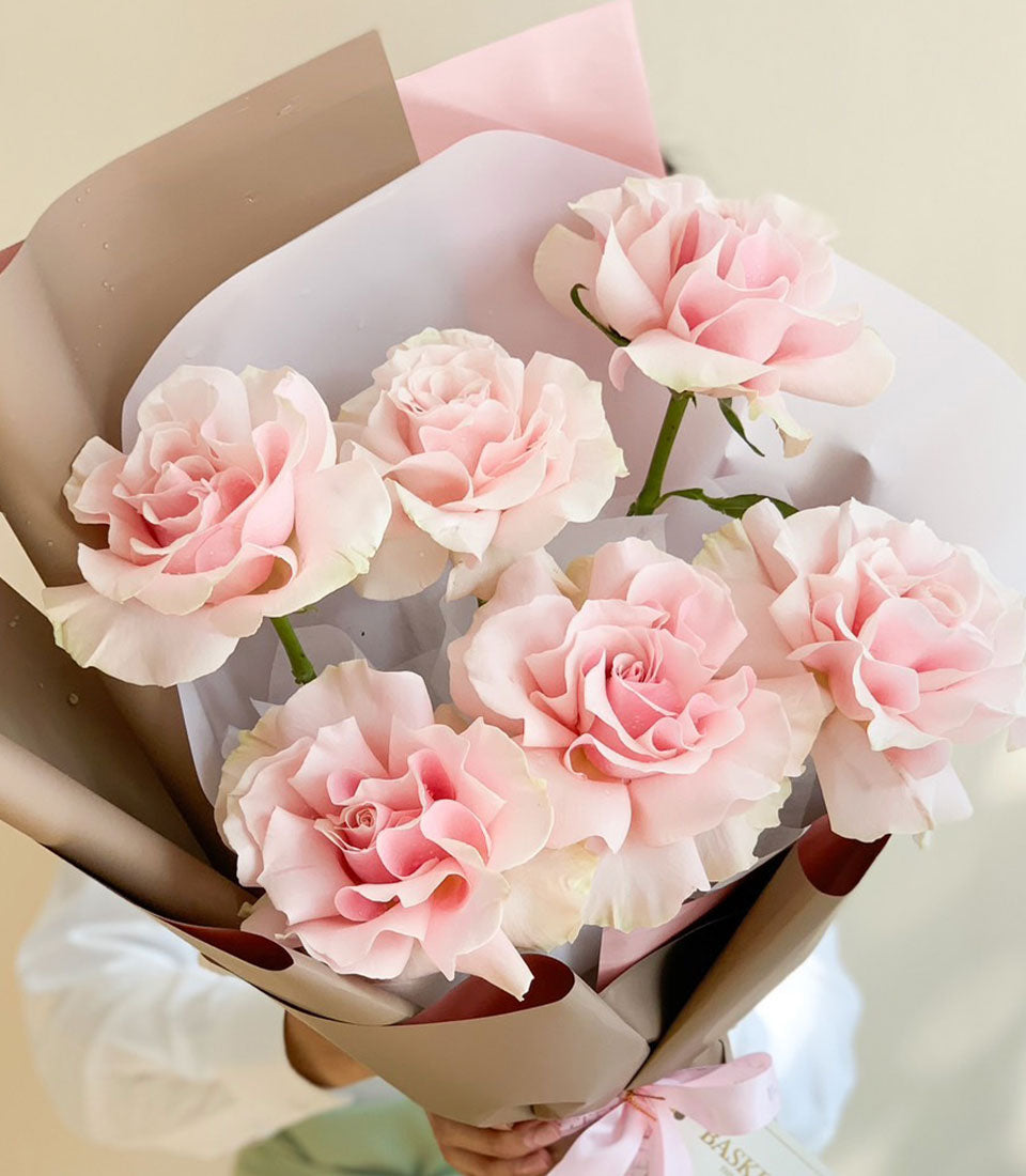 Soft pink rose bouquet with seven layered petals, wrapped in kraft paper and pink ribbon for anniversary celebrations