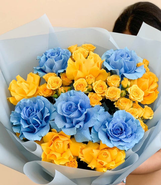 Vibrant blue and yellow rose bouquet with fresh water-kissed petals, graduation gift wrapped in soft tissue