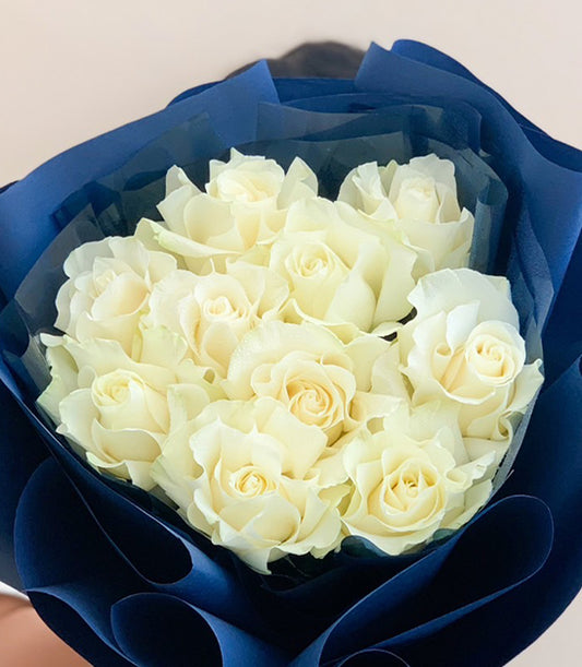 Fresh white roses bouquet with dark blue wrap, elegantly arranged for gifting