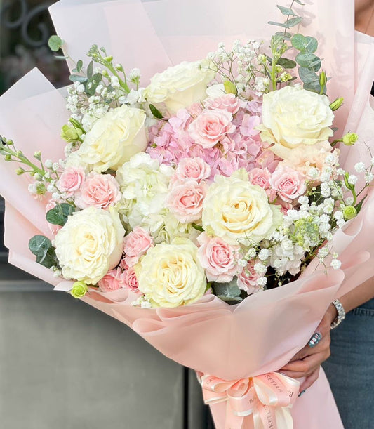 White and pink rose bouquet with hydrangeas and baby's breath, wrapped in light pink paper