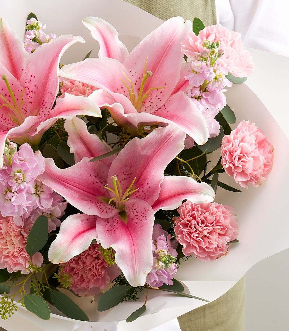 Fresh pink stargazer lilies with carnations and eucalyptus in white and olive green wrapping