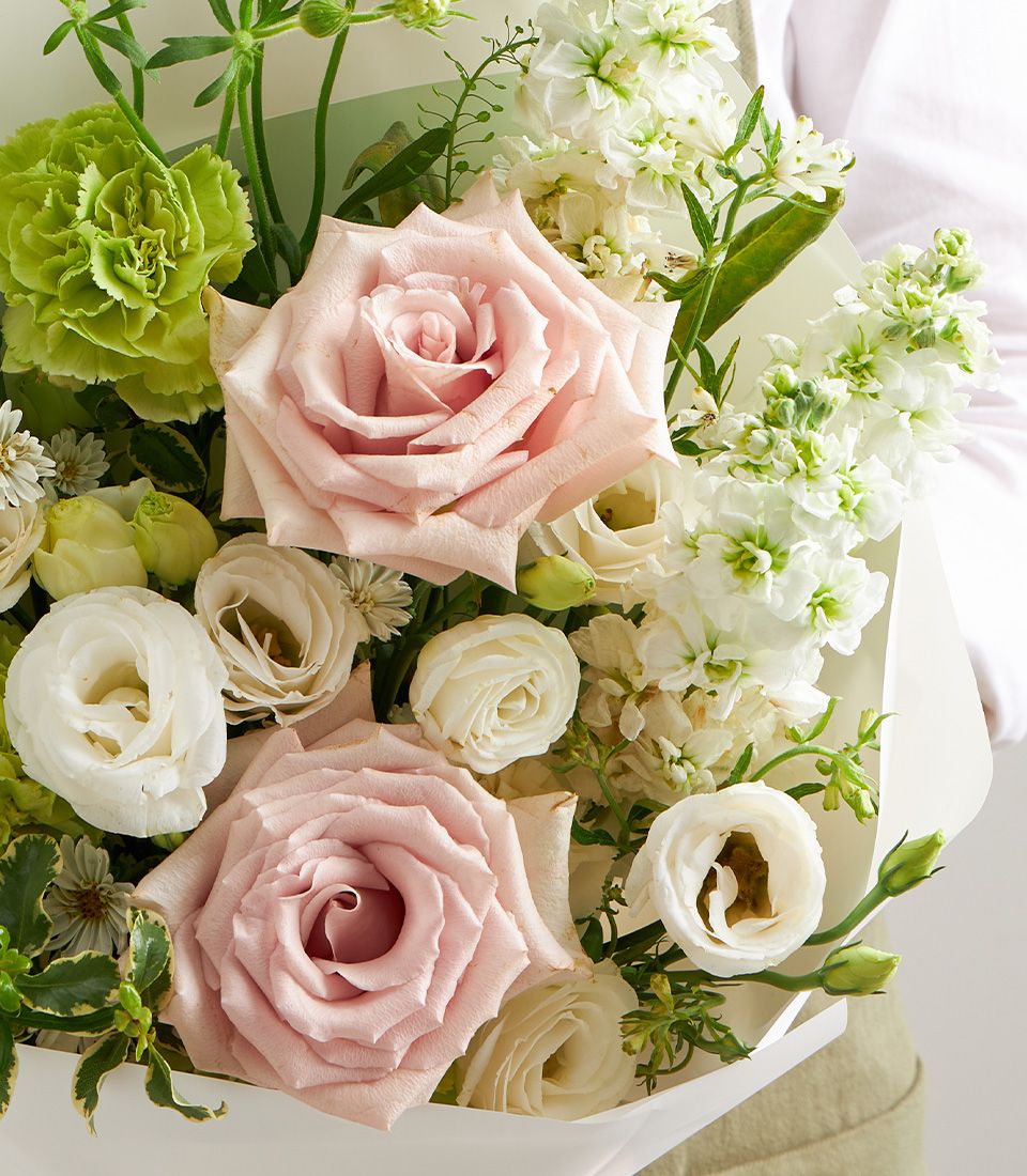 Light pink roses and cream eustoma petite bouquet with green carnations, hand-tied in pale paper wrap