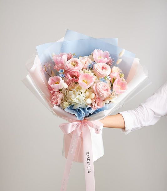 Pastel pink and blue fresh flower bouquet with roses, tulips and hydrangeas, tied with Basketeer ribbon