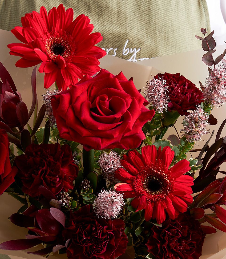 Passionate red mixed flower bouquet with roses, gerbera daisies, and carnations in vibrant scarlet and burgundy tones
