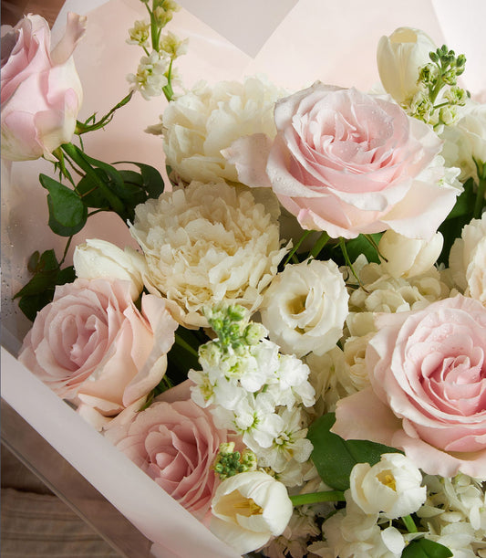 Fresh pink roses and white peonies bouquet with tulips and stock flowers in light pink wrapping