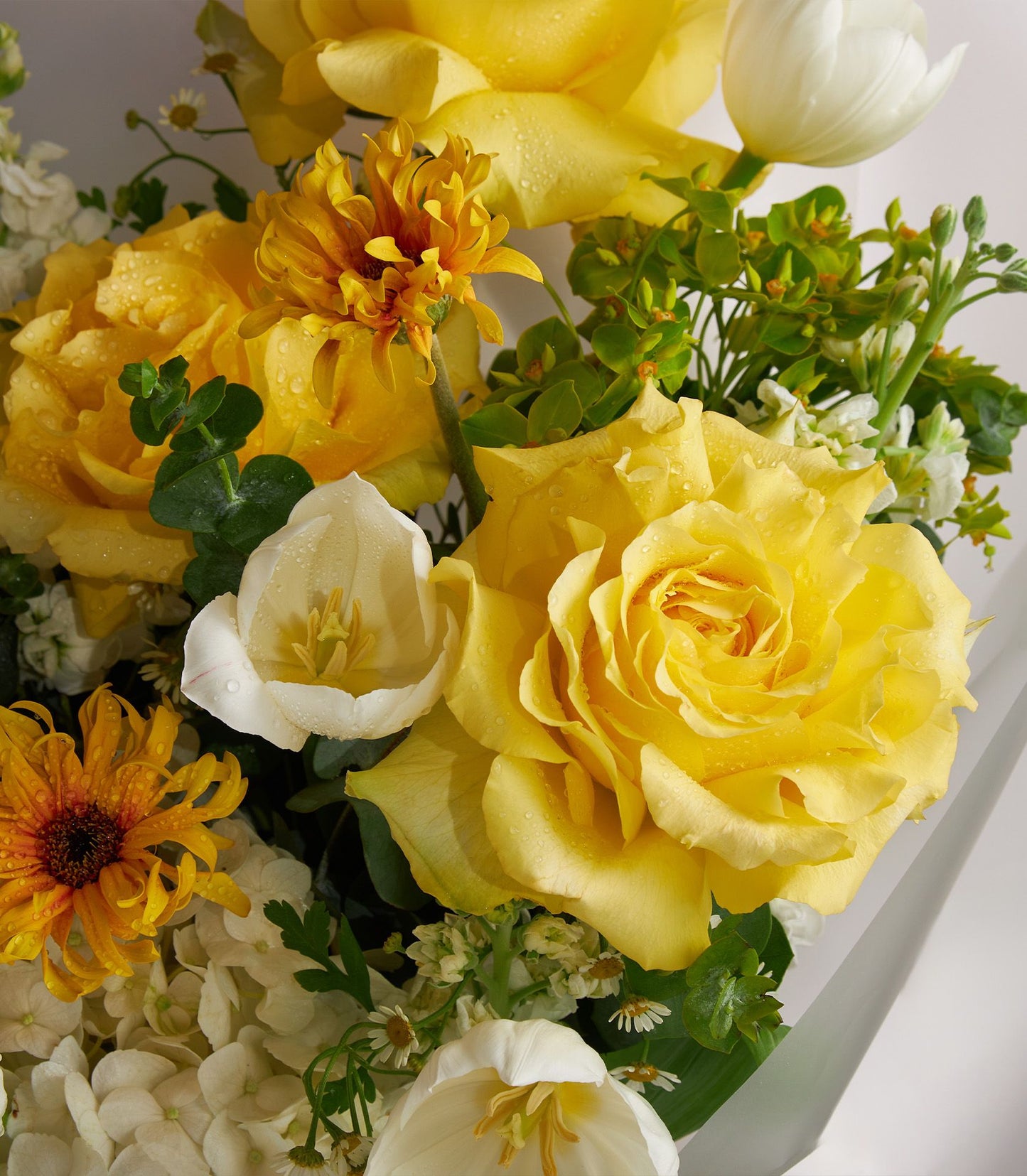Vibrant sunshine yellow roses and white tulips fresh flower bouquet with filler flowers
