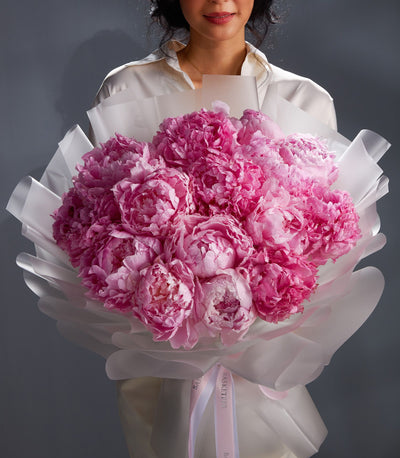Fresh pink peony bouquet with white wrap and pink ribbon, vibrant blooms for gifting