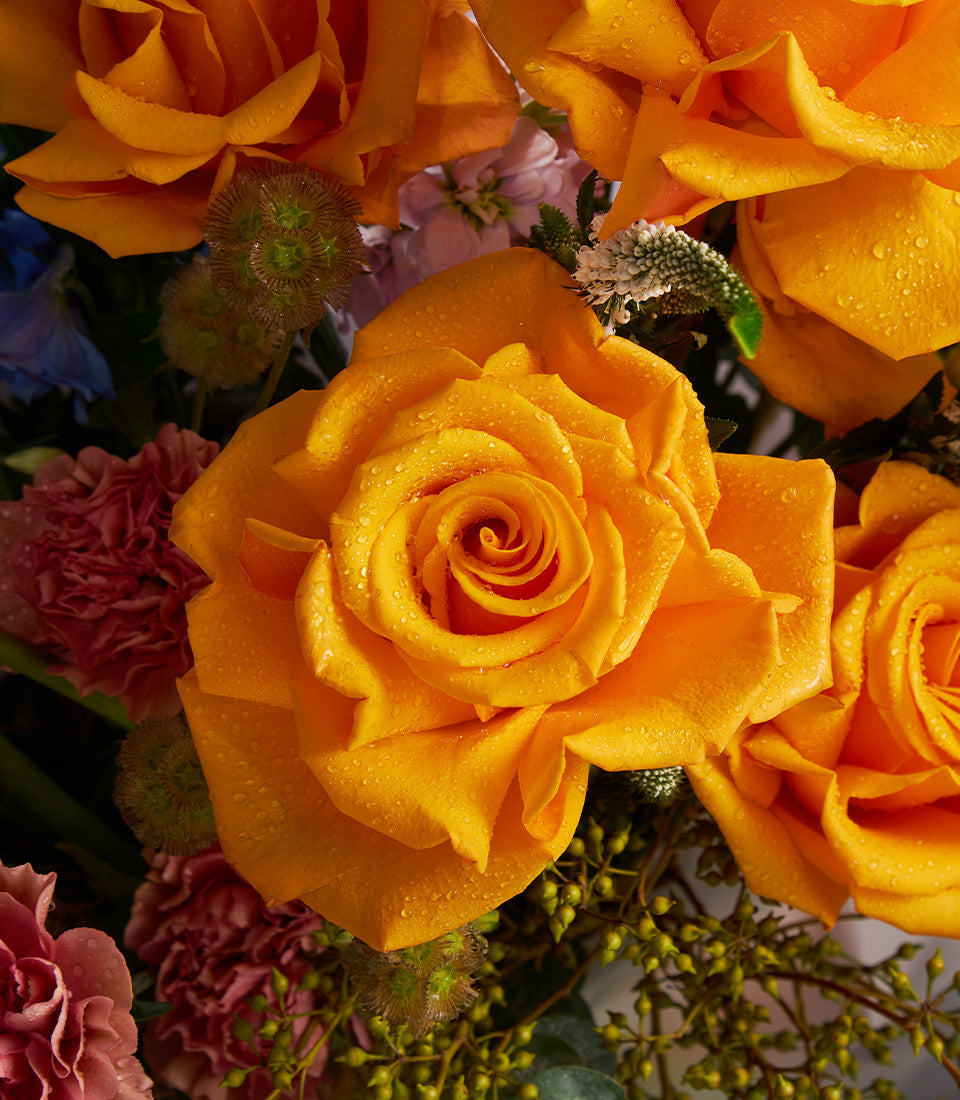 Premium mixed bouquet with orange roses, delphinium, and carnations in fresh arrangement