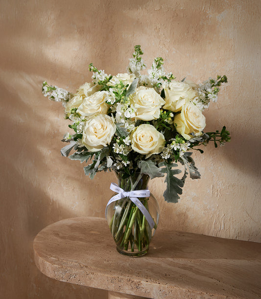 Ivory Elegance clear glass vase with white roses and dusty miller foliage, white ribbon detail