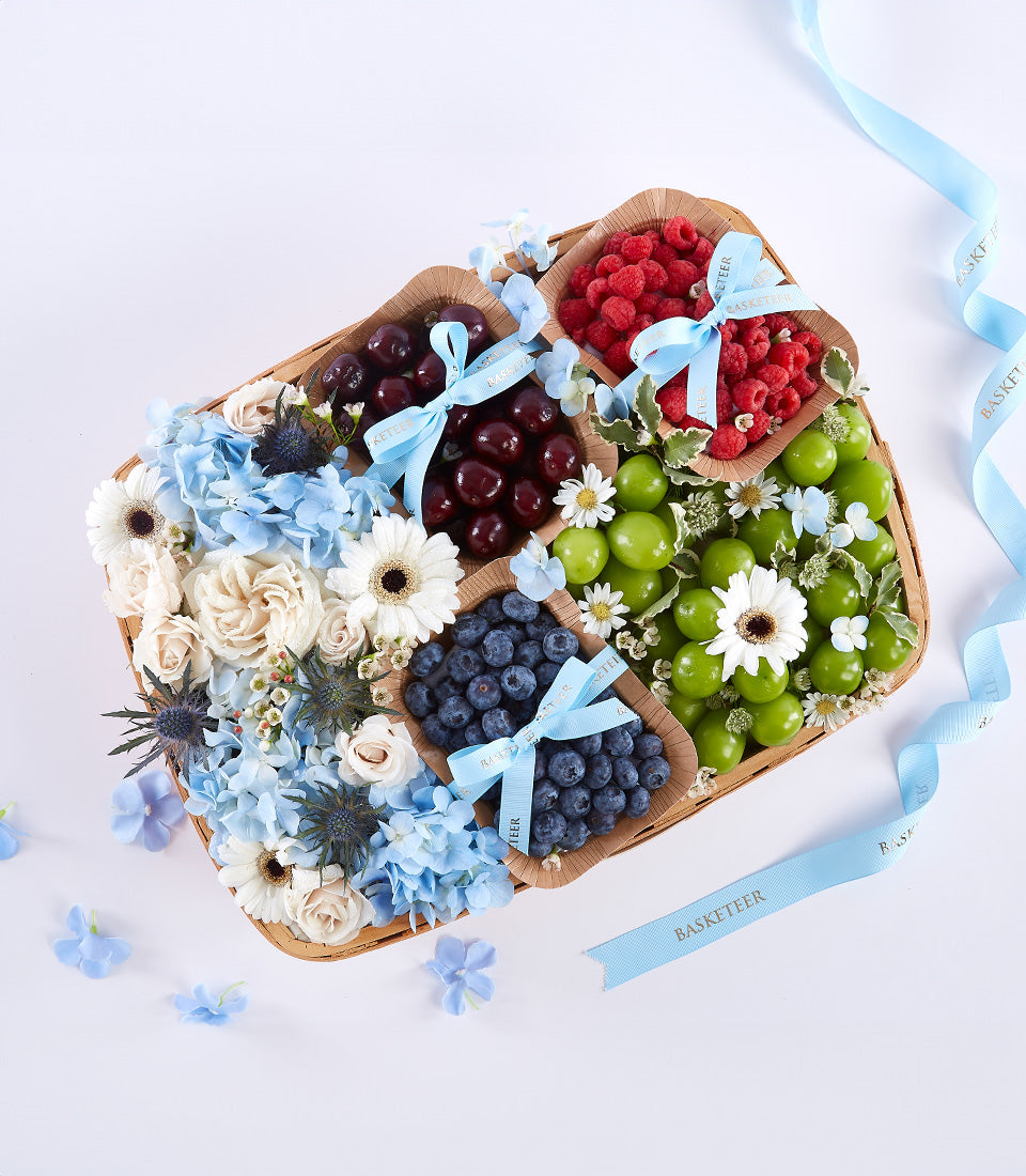 Premium Mother's Day gift basket with fresh berries, tropical fruits, white roses and blue hydrangeas