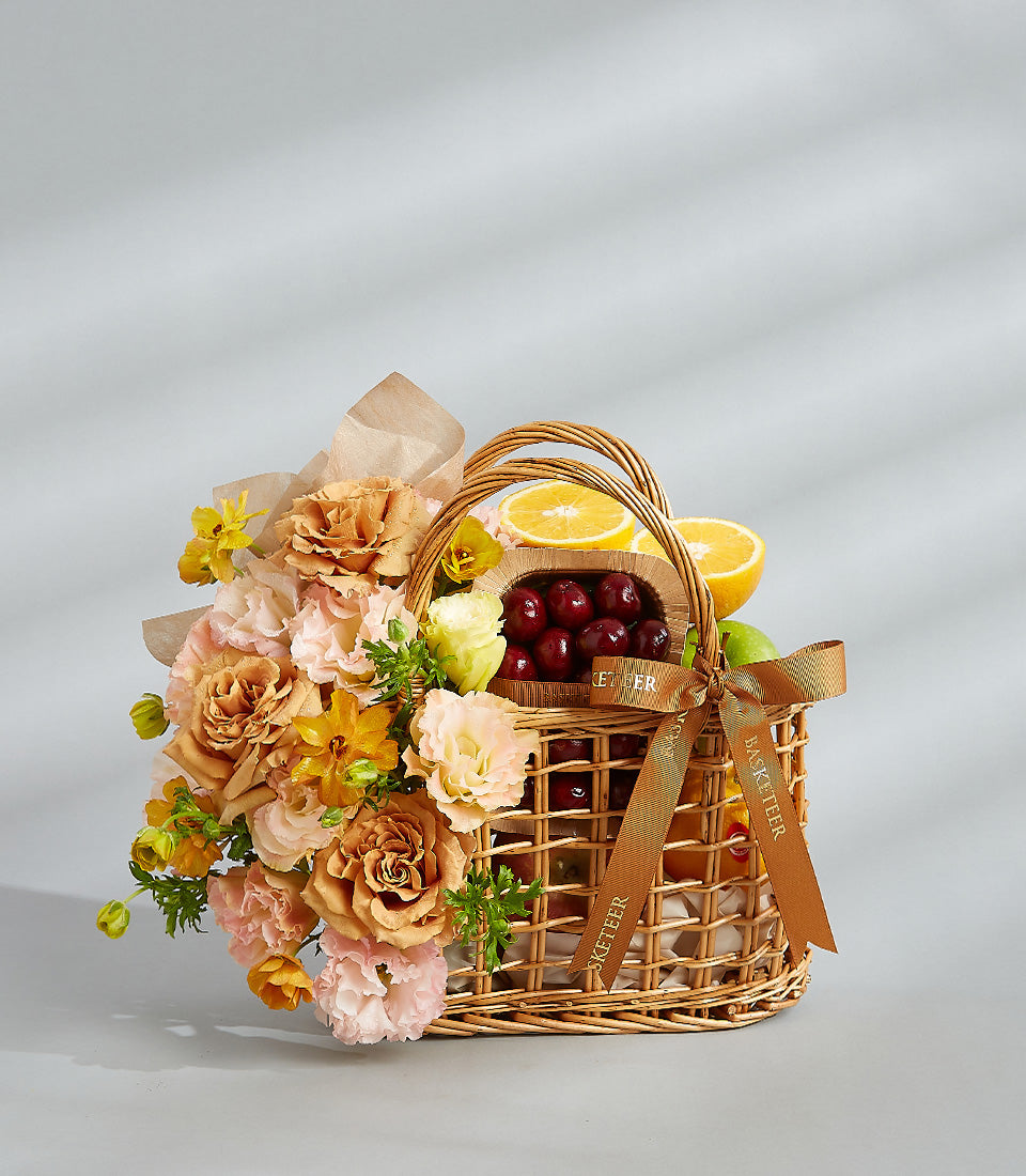 Wicker gift basket with fresh citrus, green apples, red cherries, and peach roses for birthday celebration
