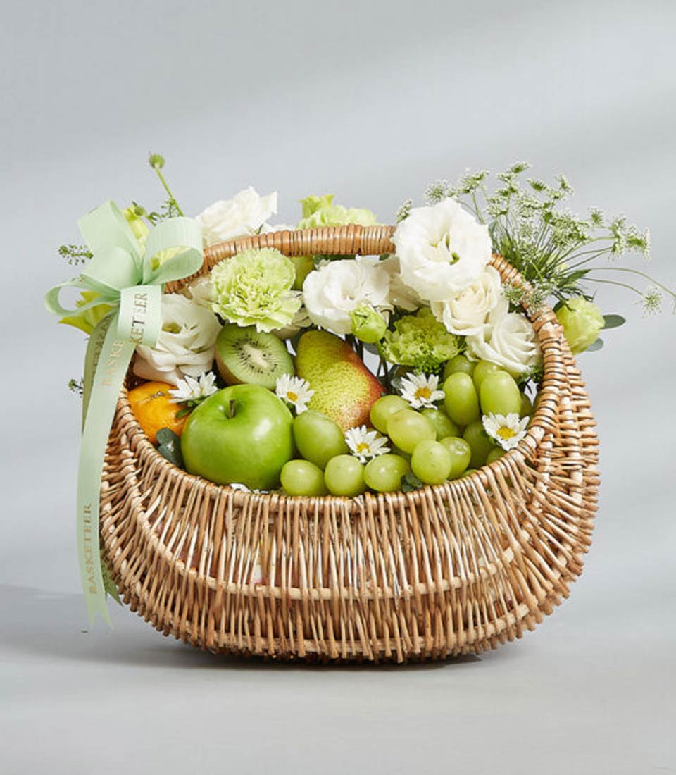 Fresh Harmony wicker basket with green apples, grapes, kiwi, pear and white flowers for birthday gifts