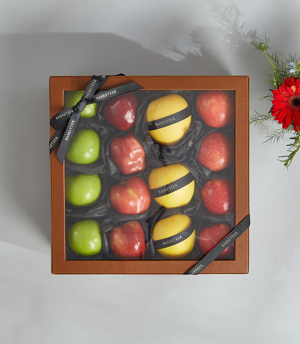 Premium gift box with twelve apples in red, green, and yellow varieties, luxury fruit presentation in compartmented leather