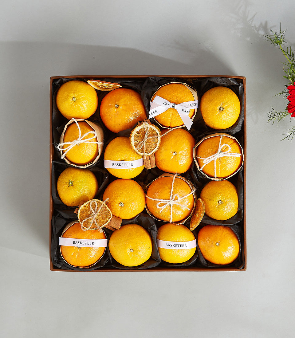 Premium citrus gift box with fresh oranges, white ribbons, and dried citrus slices in luxury leather presentation