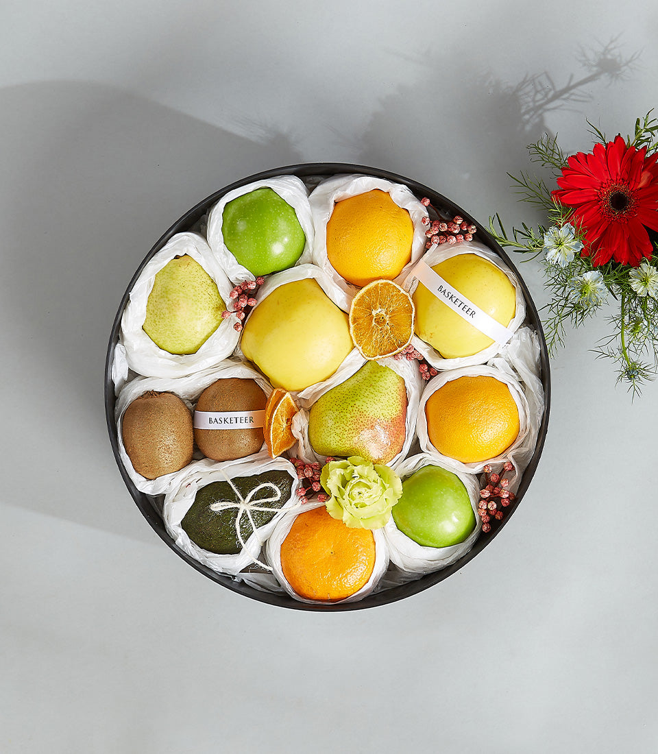 Premium citrus and pear fruit basket with individually wrapped fresh produce, dried orange slices, and rose accent