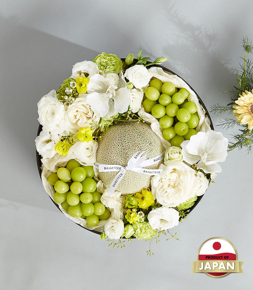 Luxury Japanese cantaloupes with white roses and green grapes in round dark gift box