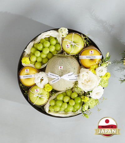 Premium Japanese melon and grape gift basket with fresh apples, roses, and white flowers in round black box