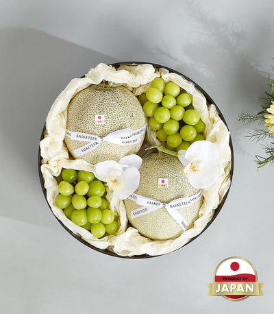 Premium Japanese cantaloupes and green grapes in black luxury gift box with white orchid accents