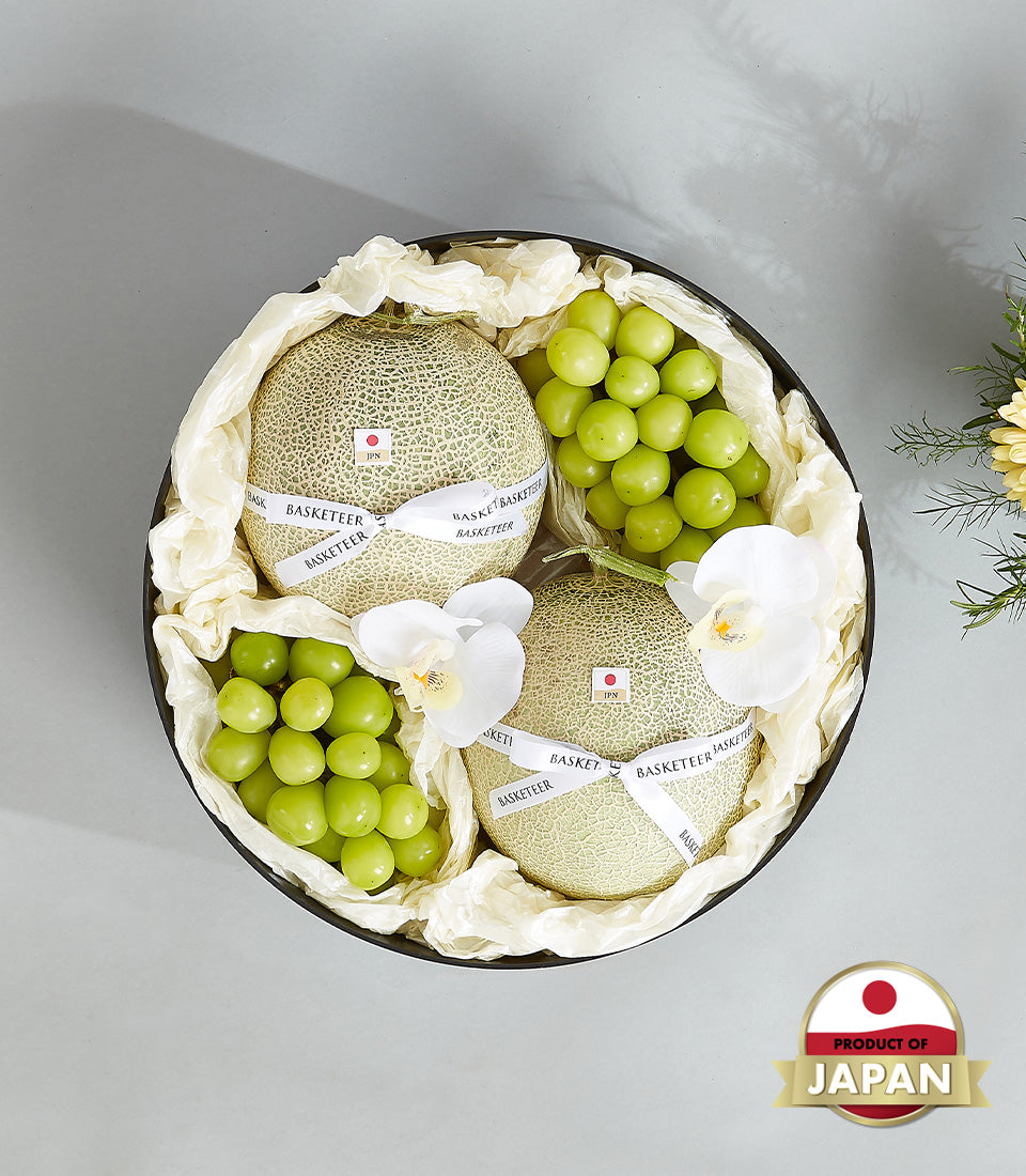 Premium Japanese cantaloupes and green grapes in black luxury gift box with white orchid accents