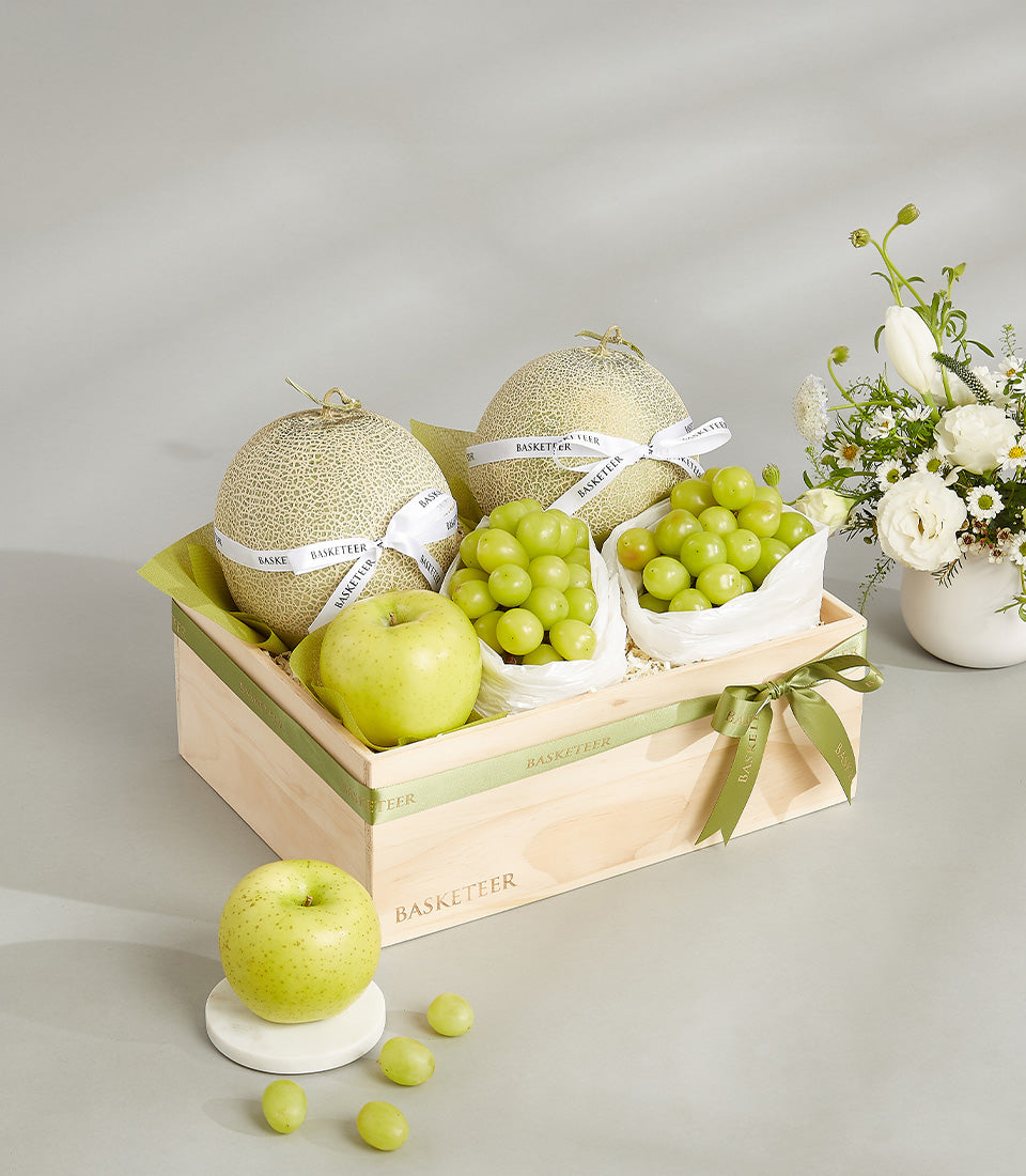 Luxury cantaloupe and green fruit gift box with white ribbons in light wooden crate