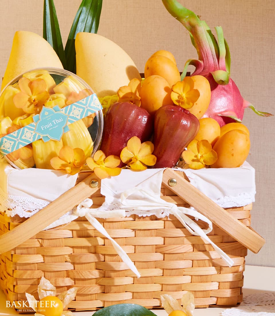 Vibrant wicker fruit basket with Thai mangoes, dragon fruit, rose apples, and fresh orchids