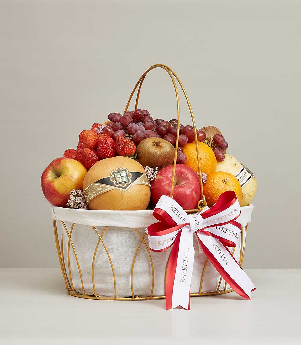 Luxury gold wire fruit basket with fresh strawberries, grapes, apples, kiwis, oranges and pears, tied with red ribbon bow