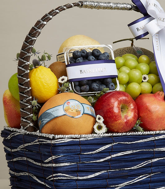 Dark blue woven fruit gift basket with fresh pears, apples, pomegranate, grapes, and berries for birthdays