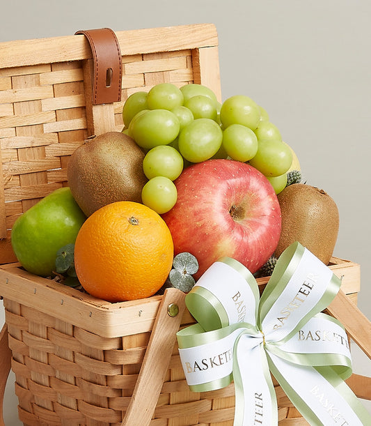 Basketeer luxury gift basket Bangkok: fresh fruit hamper with grapes, apples, kiwi, and orange in a woven wicker basket. White & green Basketeer ribbon.