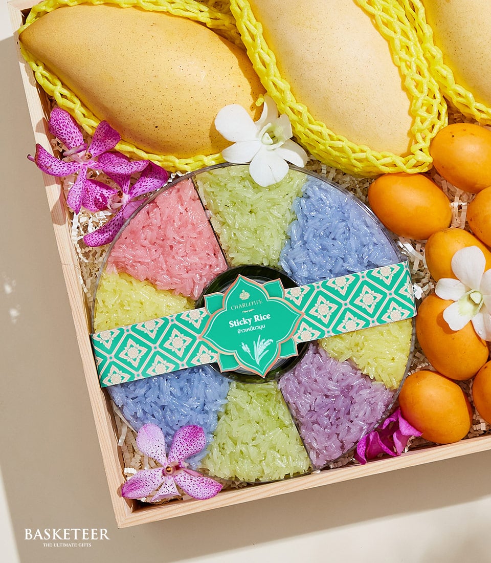 Premium mango gift box with yellow mesh-wrapped fruits, colorful sticky rice assortment, and Thai tropical citrus