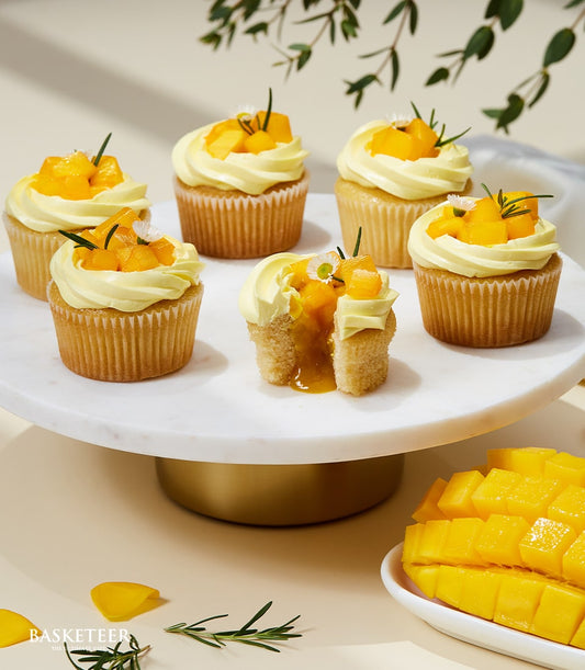 Mango cupcakes with fresh fruit topping and golden filling on marble stand