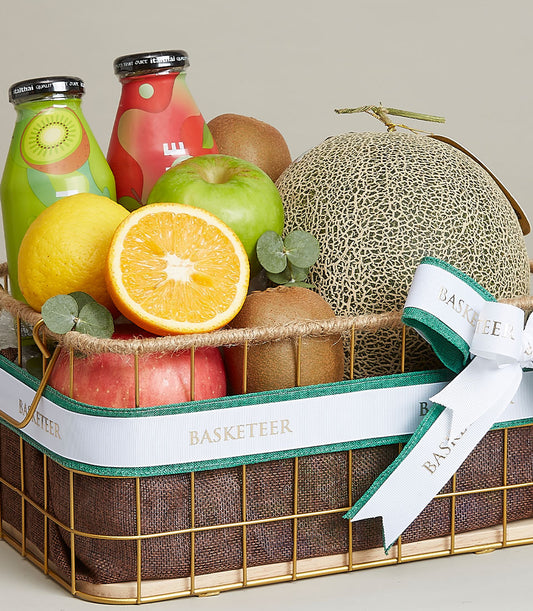 Gold wire fruit basket with fresh apples, kiwis, citrus, melon, and wellness juices