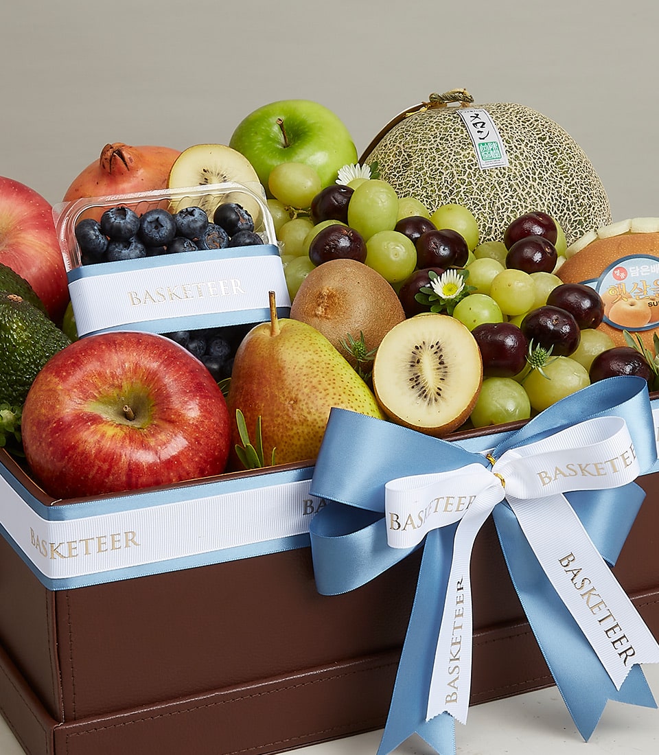 Luxury mixed fruit basket with apples, grapes, pomegranate, kiwi, and melon in dark brown leather-stitched container with