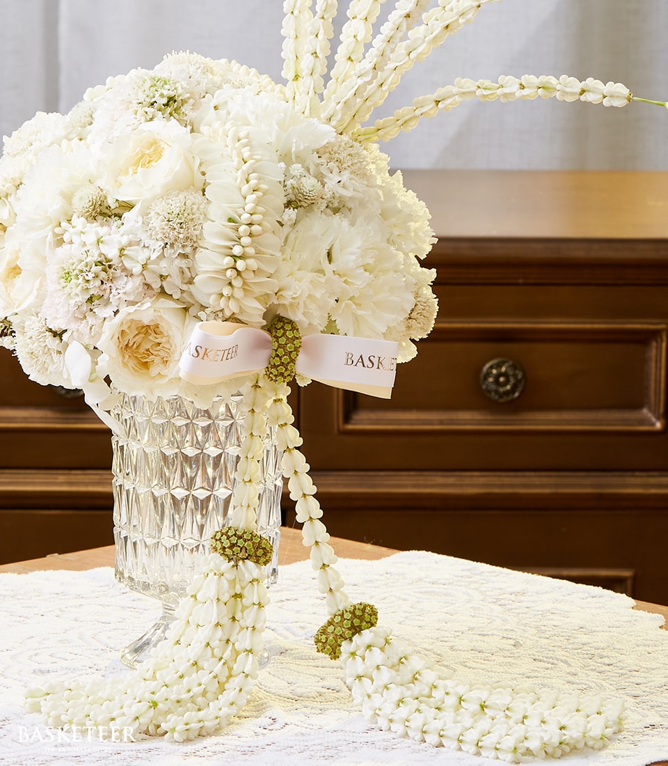 Elegant white rose and carnation arrangement in cut-glass vase with pink ribbon for Songkran celebration