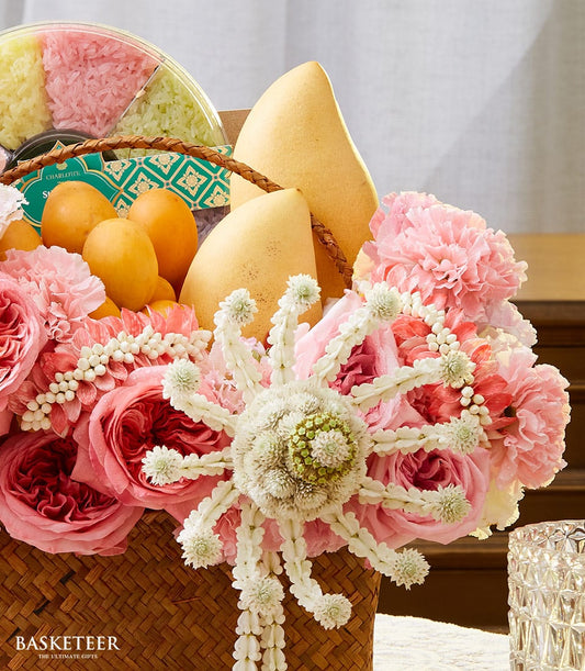 Woven gift basket with pink roses, tropical fruits, and three-color sticky rice for Thai New Year celebrations