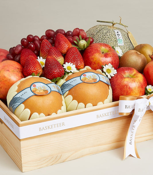 Artisan wooden gift box with fresh strawberries, apples, grapes, melon and pomegranates, tied with white ribbon